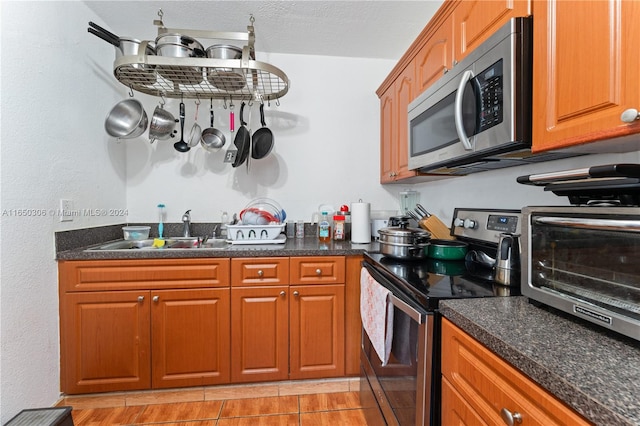 kitchen with light tile patterned floors, stainless steel appliances, a textured ceiling, and sink