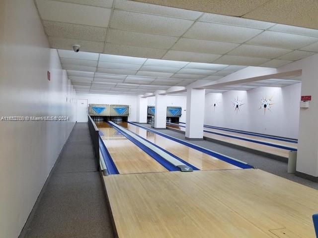 playroom featuring bowling, a baseboard radiator, and a drop ceiling