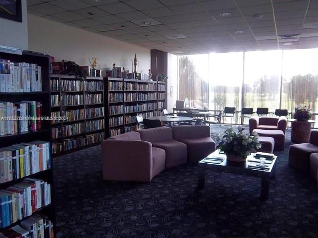 living area with a paneled ceiling and carpet