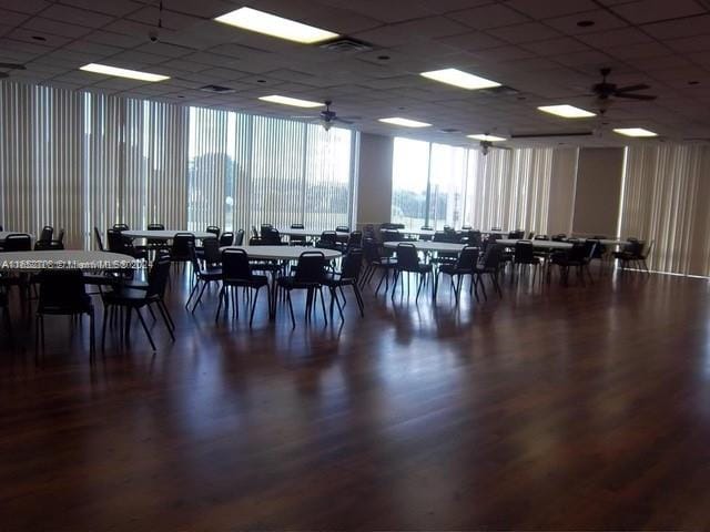 dining area with dark hardwood / wood-style flooring, a paneled ceiling, ceiling fan, and a wall of windows