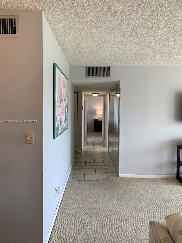 hallway featuring carpet flooring and a textured ceiling