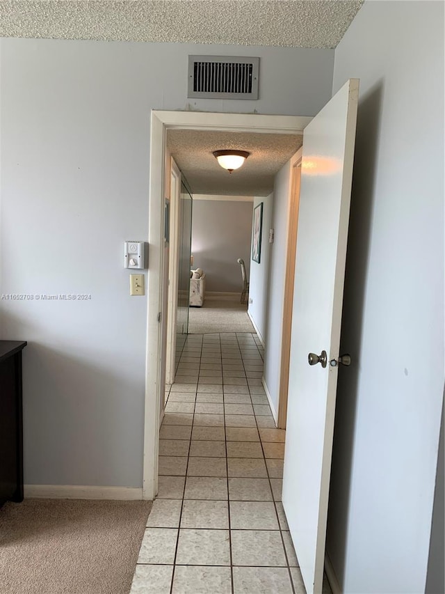 corridor featuring light colored carpet and a textured ceiling