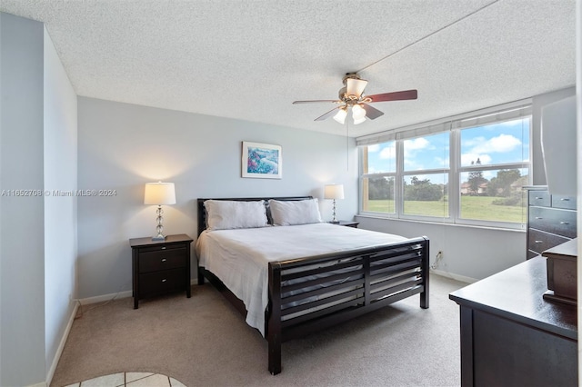 bedroom with a textured ceiling, ceiling fan, and light carpet