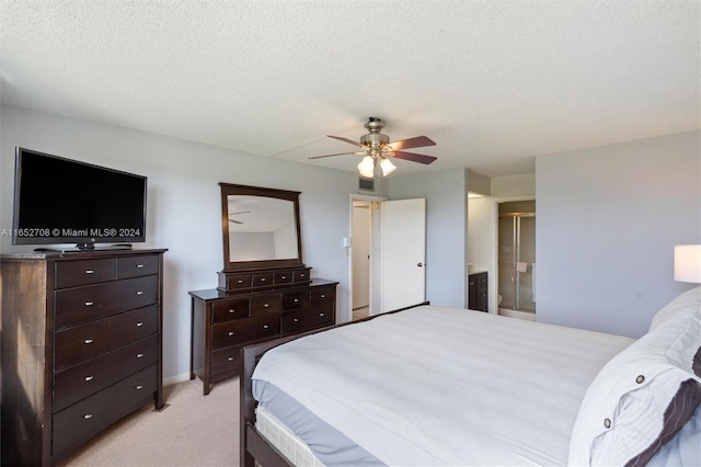 bedroom with ceiling fan, a textured ceiling, light carpet, and ensuite bath