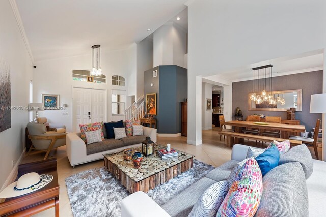 living room with an inviting chandelier, ornamental molding, light tile patterned flooring, baseboards, and stairs