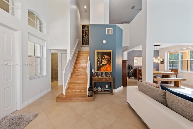 entryway featuring stairs, a high ceiling, light tile patterned floors, and visible vents