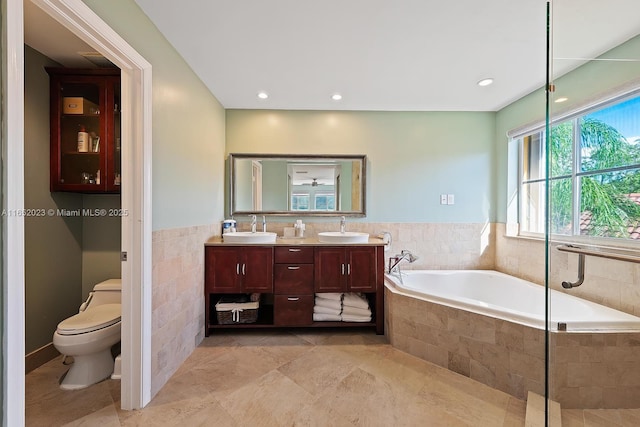 bathroom featuring a garden tub, double vanity, a sink, and toilet