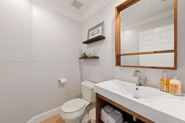 half bath featuring baseboards, visible vents, toilet, ornamental molding, and vanity