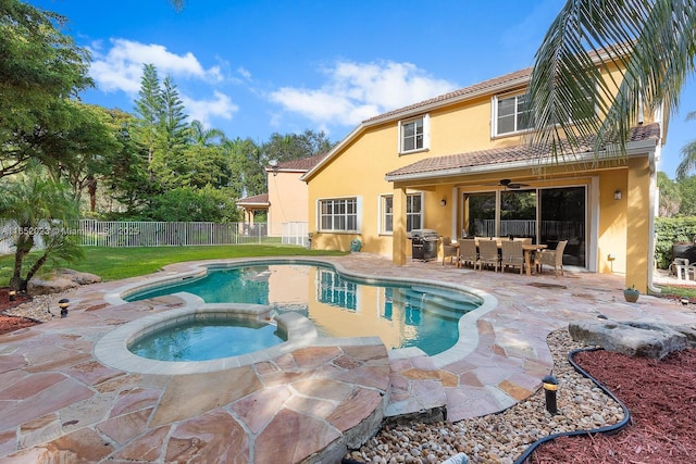 view of swimming pool with a patio, ceiling fan, grilling area, fence, and a pool with connected hot tub