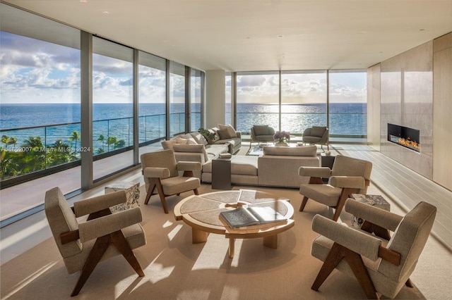 sunroom / solarium featuring a tiled fireplace and a water view