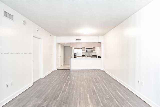 unfurnished living room featuring hardwood / wood-style flooring and a textured ceiling