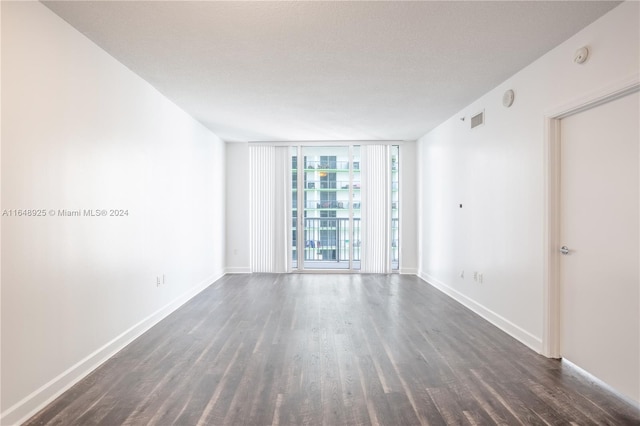 unfurnished room featuring dark wood-type flooring, a textured ceiling, and expansive windows