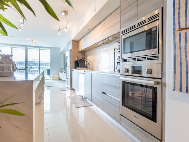 kitchen with track lighting, appliances with stainless steel finishes, light tile patterned floors, and sink