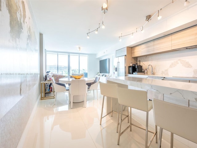 kitchen with rail lighting, light tile patterned floors, decorative backsplash, and stainless steel fridge with ice dispenser