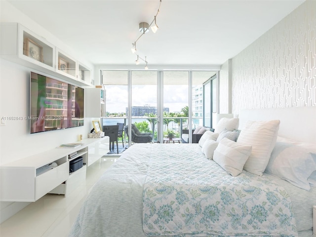 tiled bedroom featuring rail lighting, floor to ceiling windows, and access to outside