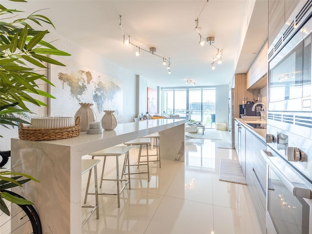 kitchen with black electric stovetop, light tile patterned flooring, and a kitchen breakfast bar