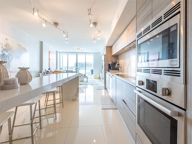 kitchen with light tile patterned floors, rail lighting, a breakfast bar area, and stainless steel appliances