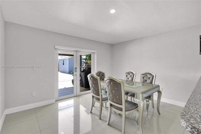 dining room with light tile patterned floors, a textured ceiling, and french doors