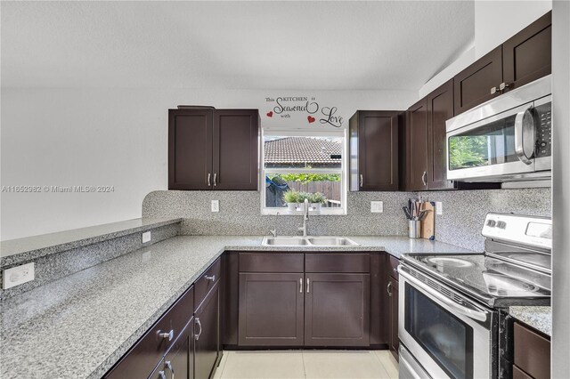 kitchen featuring light tile patterned floors, stainless steel appliances, sink, dark brown cabinets, and tasteful backsplash