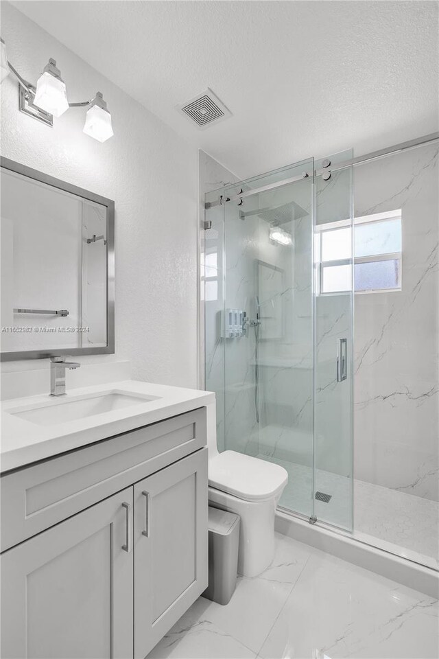 bathroom with vanity, toilet, a textured ceiling, and a shower with door