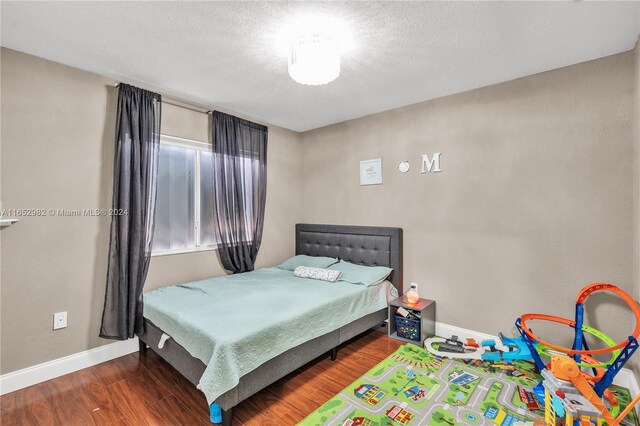 bedroom featuring dark hardwood / wood-style flooring and a textured ceiling