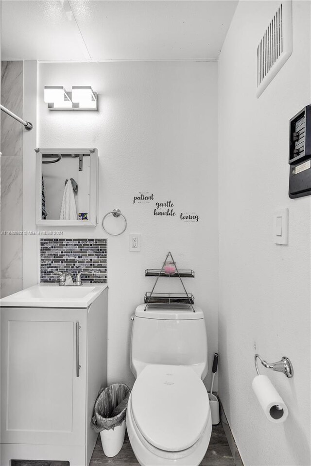 bathroom featuring vanity, toilet, and tasteful backsplash