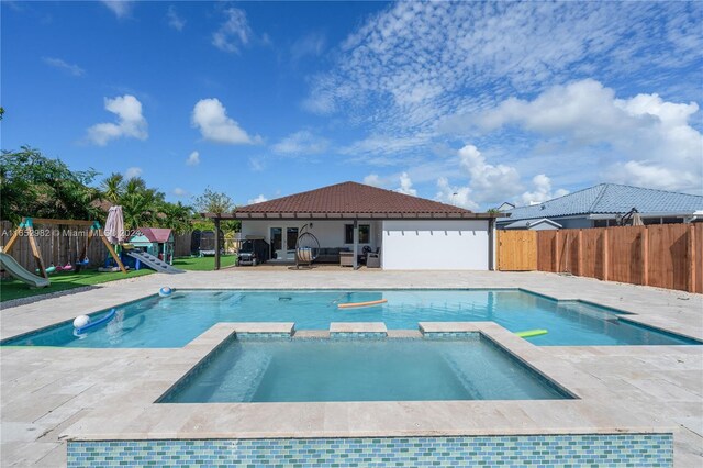 view of pool featuring a patio area, an in ground hot tub, and a playground