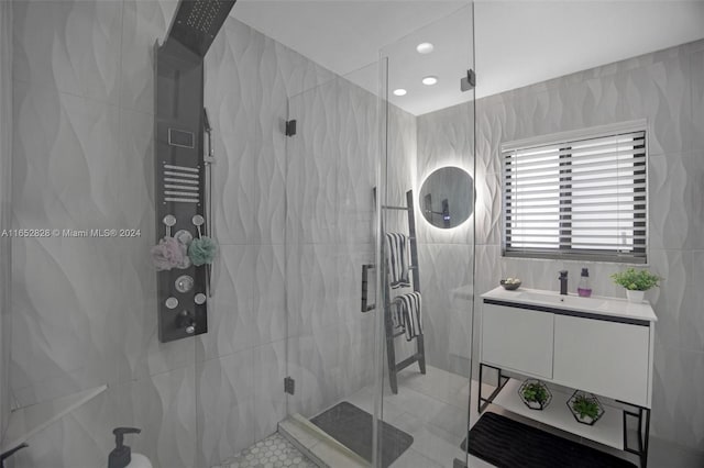 bathroom with tile walls, vanity, tile patterned floors, and a shower with shower door