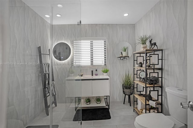 bathroom featuring tile walls, tile patterned floors, a shower with door, and vanity