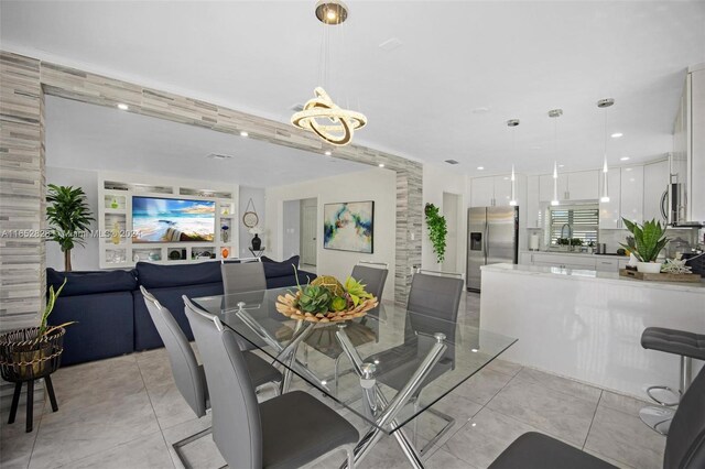 dining area featuring a notable chandelier, light tile patterned floors, and sink