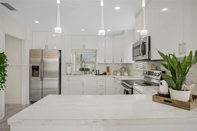 kitchen with decorative light fixtures, stainless steel appliances, and white cabinets