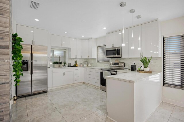 kitchen with light stone counters, pendant lighting, kitchen peninsula, white cabinetry, and appliances with stainless steel finishes