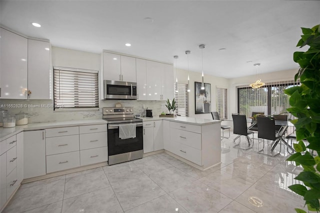 kitchen with appliances with stainless steel finishes, decorative backsplash, white cabinets, kitchen peninsula, and pendant lighting