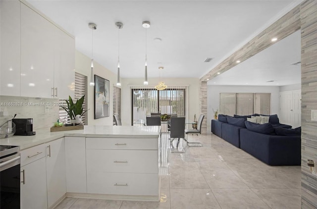 kitchen featuring white cabinetry, kitchen peninsula, backsplash, appliances with stainless steel finishes, and decorative light fixtures