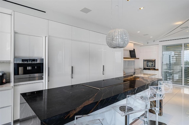 kitchen featuring white cabinetry, black electric cooktop, stainless steel oven, and a breakfast bar