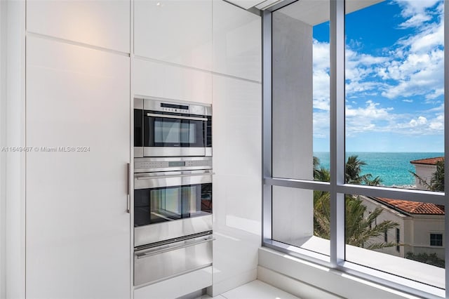 kitchen with double oven, a water view, and white cabinets