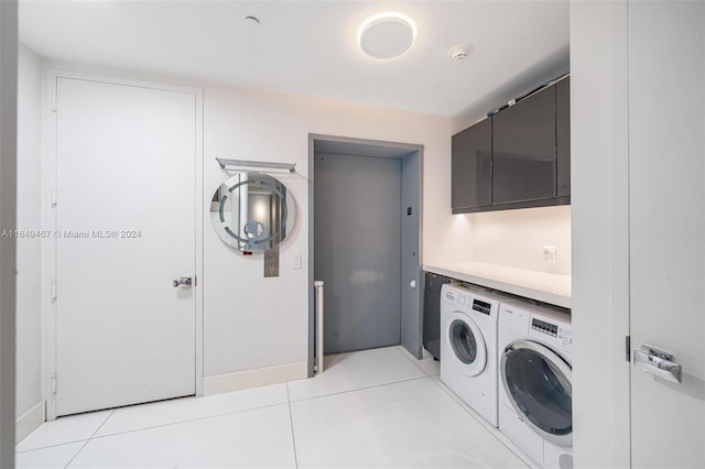 washroom featuring cabinets, washer and clothes dryer, and light tile patterned flooring