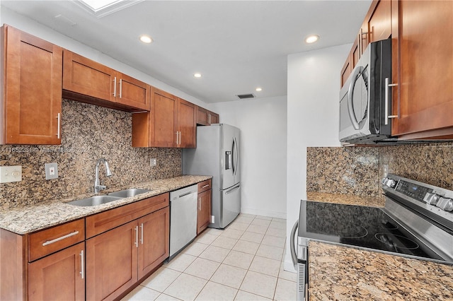 kitchen with decorative backsplash, light tile patterned flooring, light stone countertops, stainless steel appliances, and sink