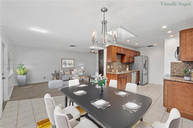 dining room featuring ceiling fan with notable chandelier, light wood-type flooring, and sink