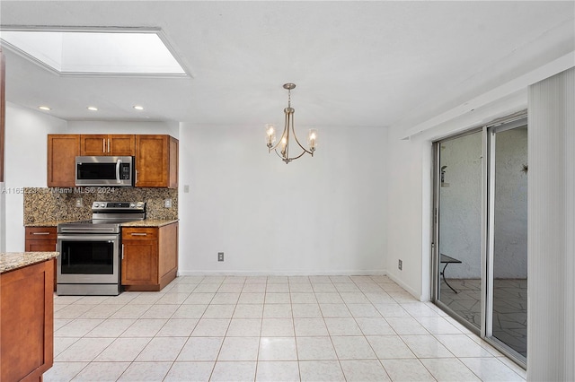 kitchen with appliances with stainless steel finishes, light stone countertops, a chandelier, and a skylight