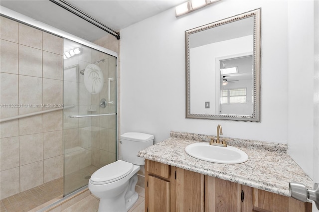 bathroom featuring tile patterned flooring, walk in shower, vanity, and toilet