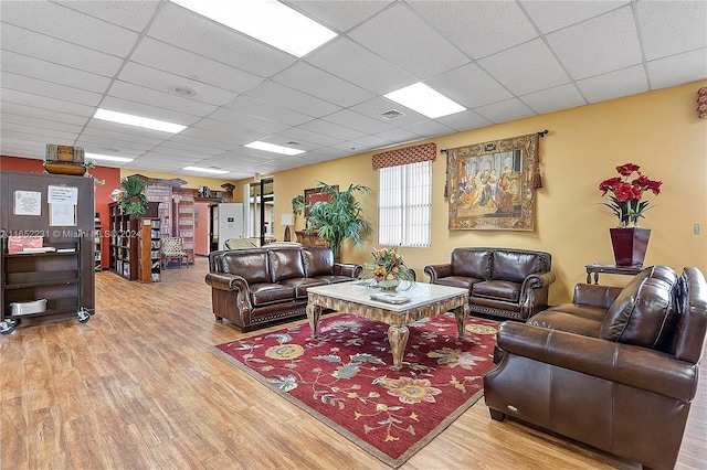 living room featuring light hardwood / wood-style flooring and a drop ceiling