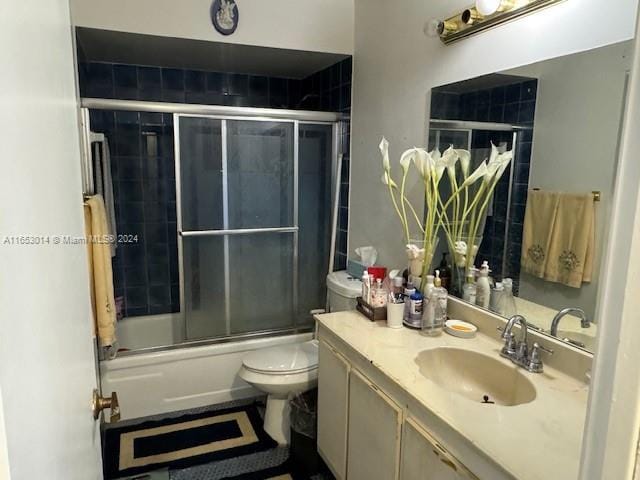 full bathroom featuring vanity, combined bath / shower with glass door, and toilet