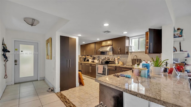 kitchen featuring stainless steel range with electric stovetop, tasteful backsplash, light tile patterned floors, sink, and light stone countertops