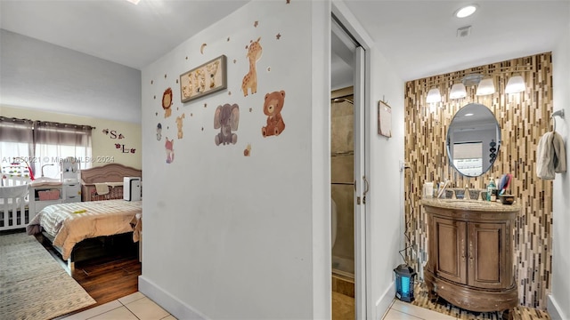 corridor with visible vents, baseboards, light tile patterned flooring, and a sink