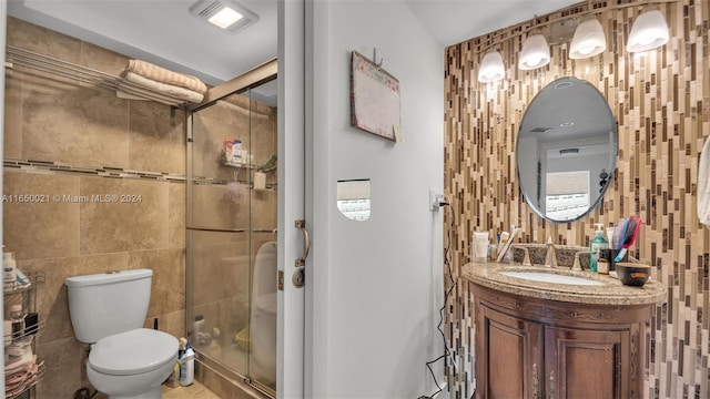 bathroom featuring toilet, tile walls, vanity, and a stall shower