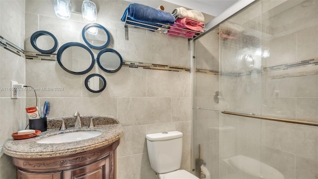 bathroom with vanity, toilet, walk in shower, and tile walls