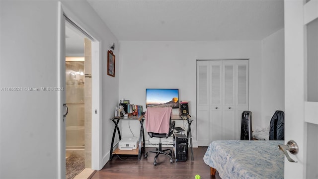 bedroom with ensuite bath, a closet, and dark hardwood / wood-style flooring