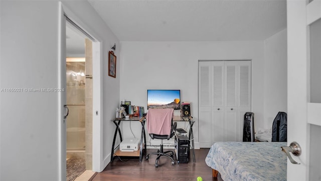 bedroom featuring baseboards, ensuite bathroom, a closet, and dark wood-style floors