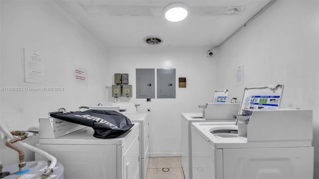 clothes washing area featuring light tile patterned floors, electric panel, and washing machine and clothes dryer